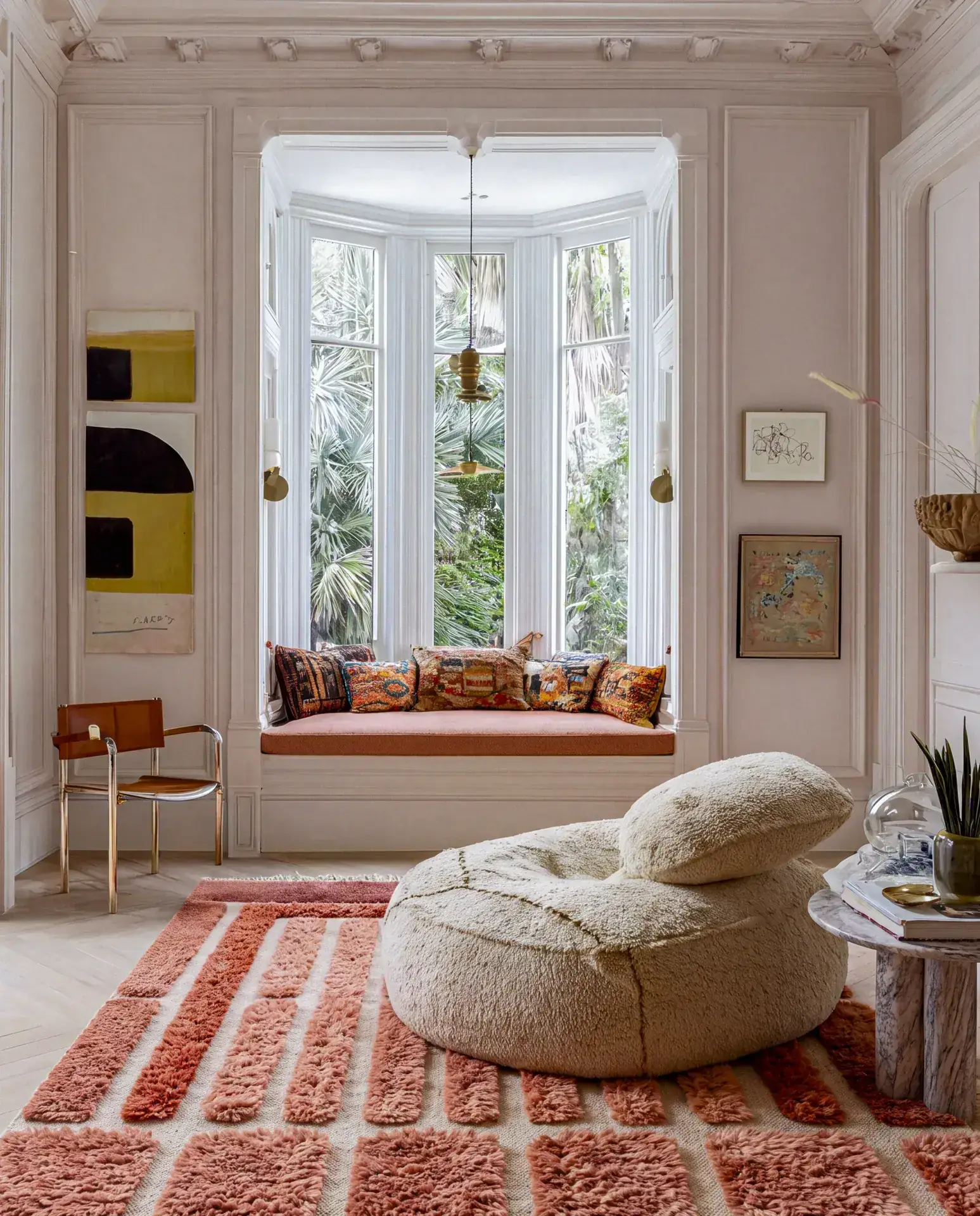 Kasbah Coral & Burgundy hand-knotted Beni Mrirt rug under a bouclé floor pouf beside a bay window seat