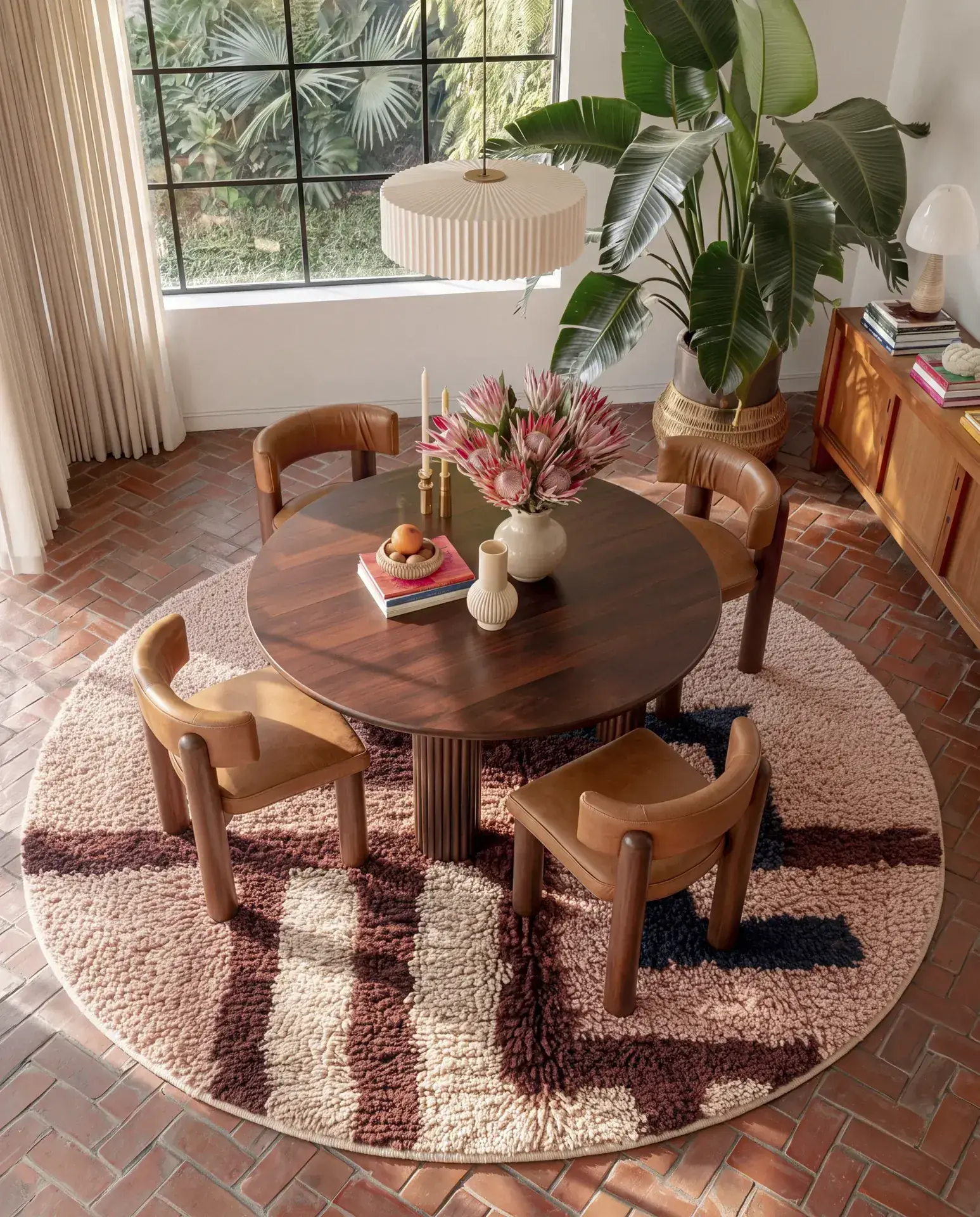 Mataha Peach & Rust handmade Berber round rug under a round wood dining table and four leather chairs on brick floors