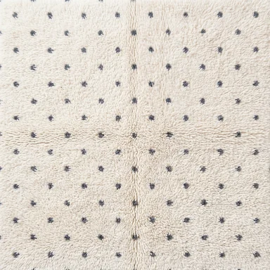 Small charcoal dots on ivory wool