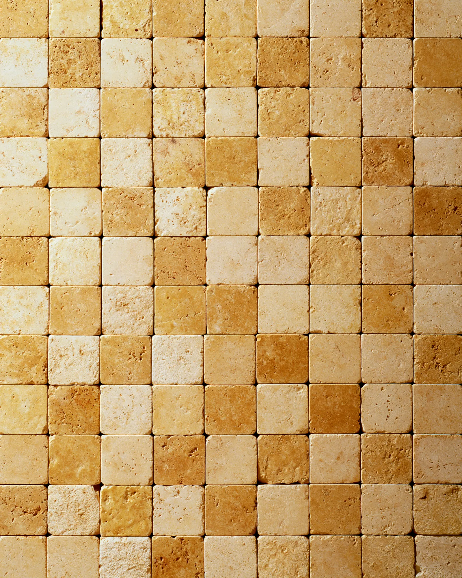 Square blocks of golden ochre stone set side by side, the inspiration for the Bejmat Ochre rug