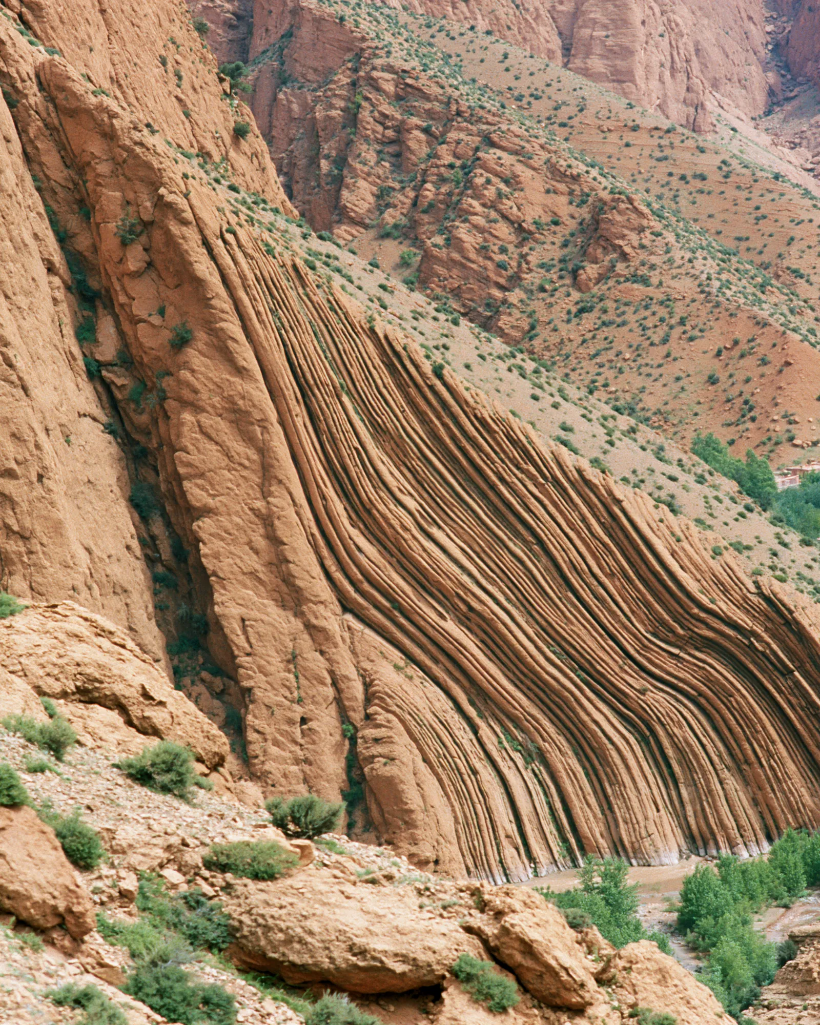 A banded rust sandstone cliff with folded layers, the inspiration for the Dades Camel rug