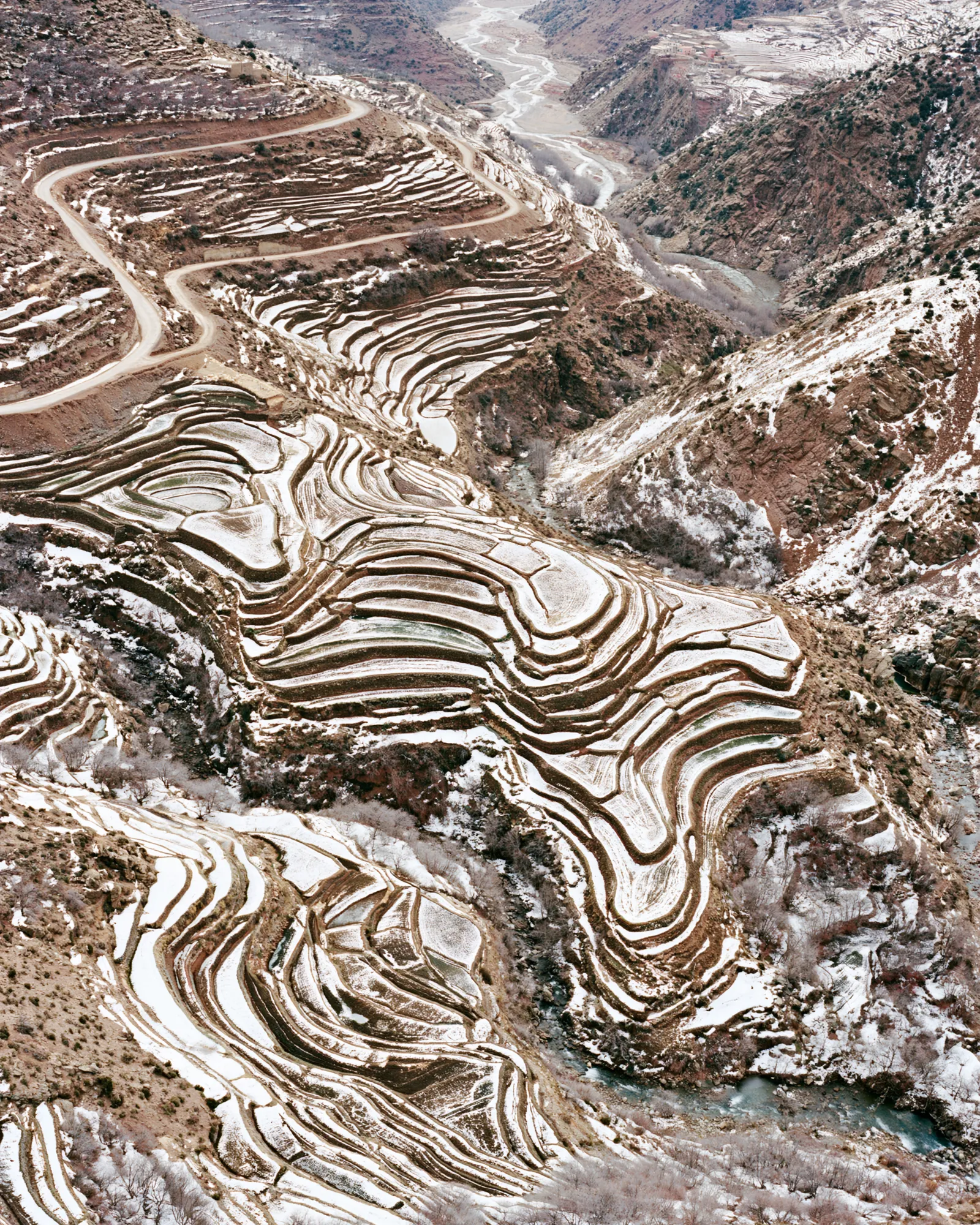Snow-dusted terraced hills above a river valley, seen from above, the inspiration for the Hamada Ivory rug
