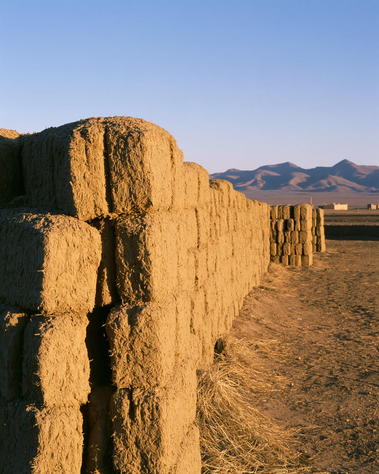 Stacked ochre mud bricks in golden light, the inspiration for the Hamada Ochre rug