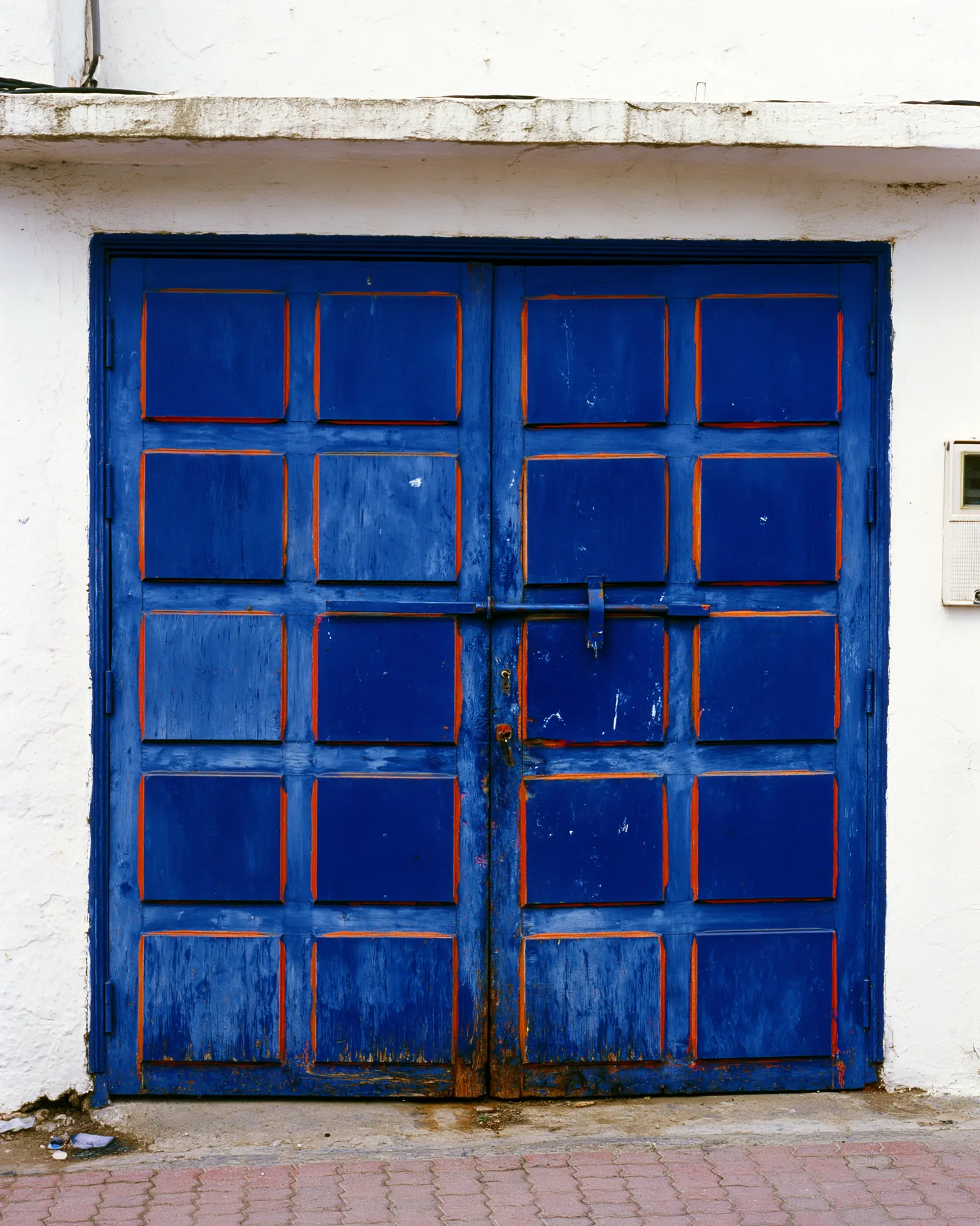 A deep blue panelled door with rust edges in a whitewashed wall, the inspiration for the Hammam Deep Teal & Ivory rug