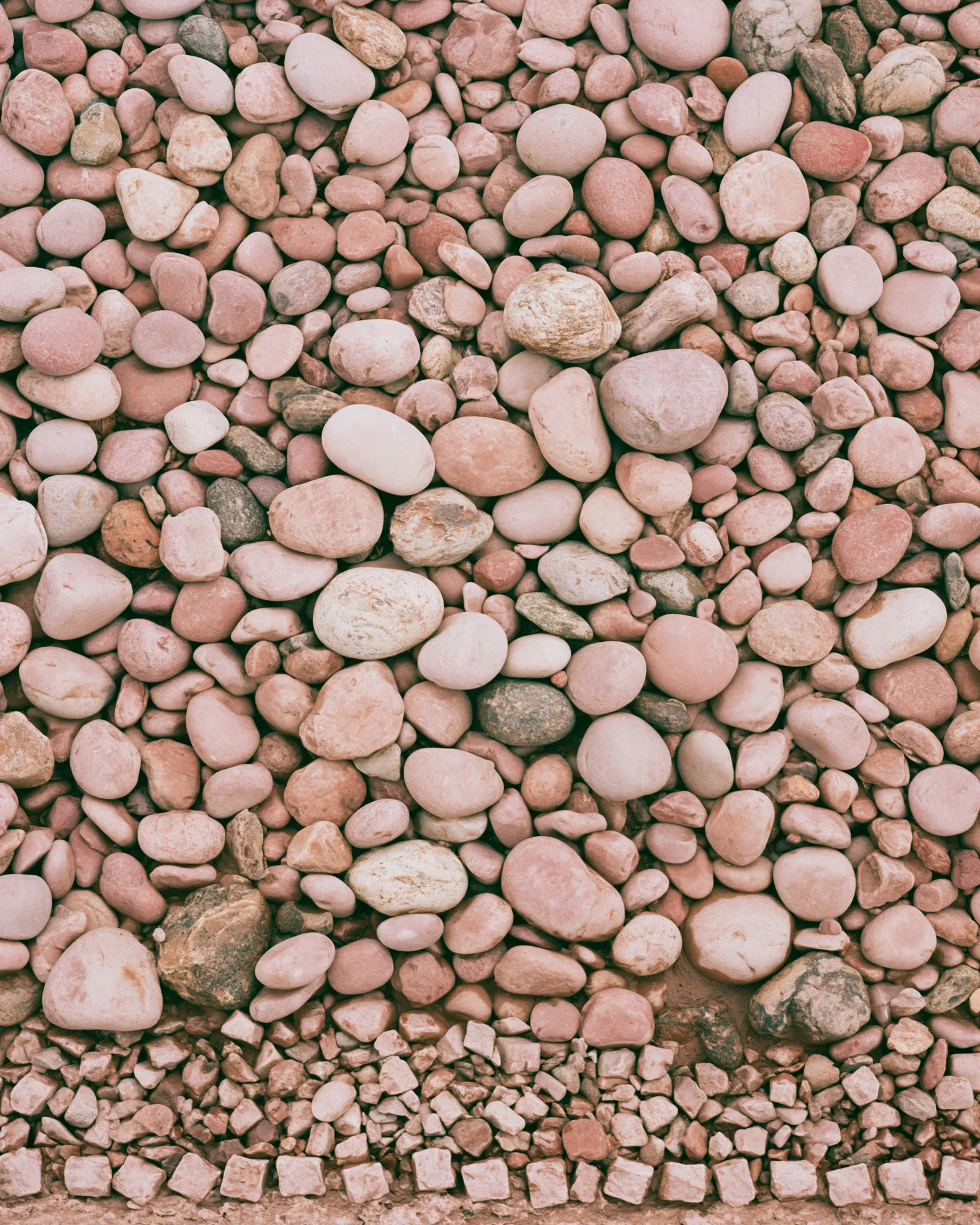 Blush and peach river stones packed together, the inspiration for the Izra Blush & Rust rug