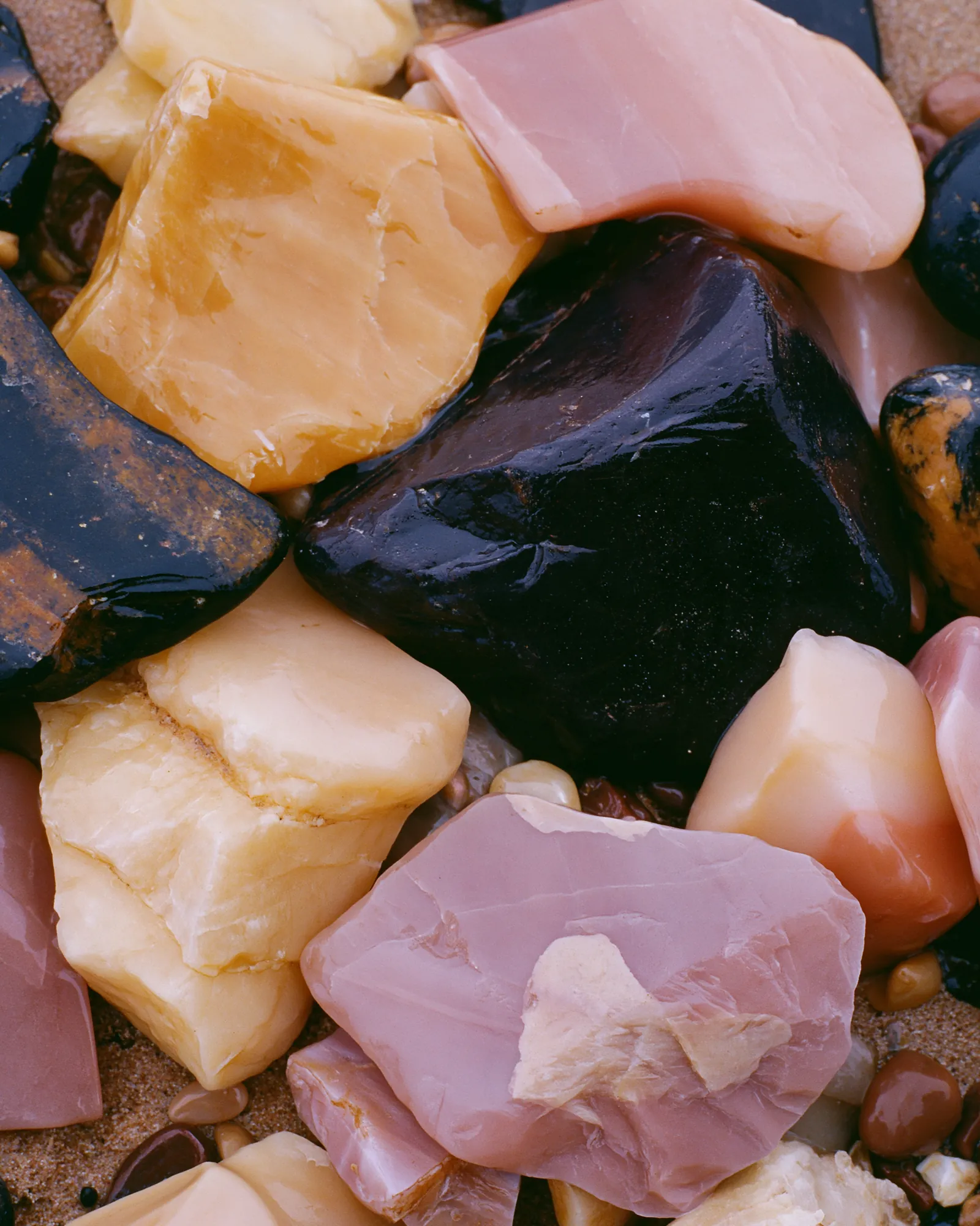 Smooth stones in peach, ivory and deep navy lying close together, the inspiration for the Seksu Pink & Orange rug