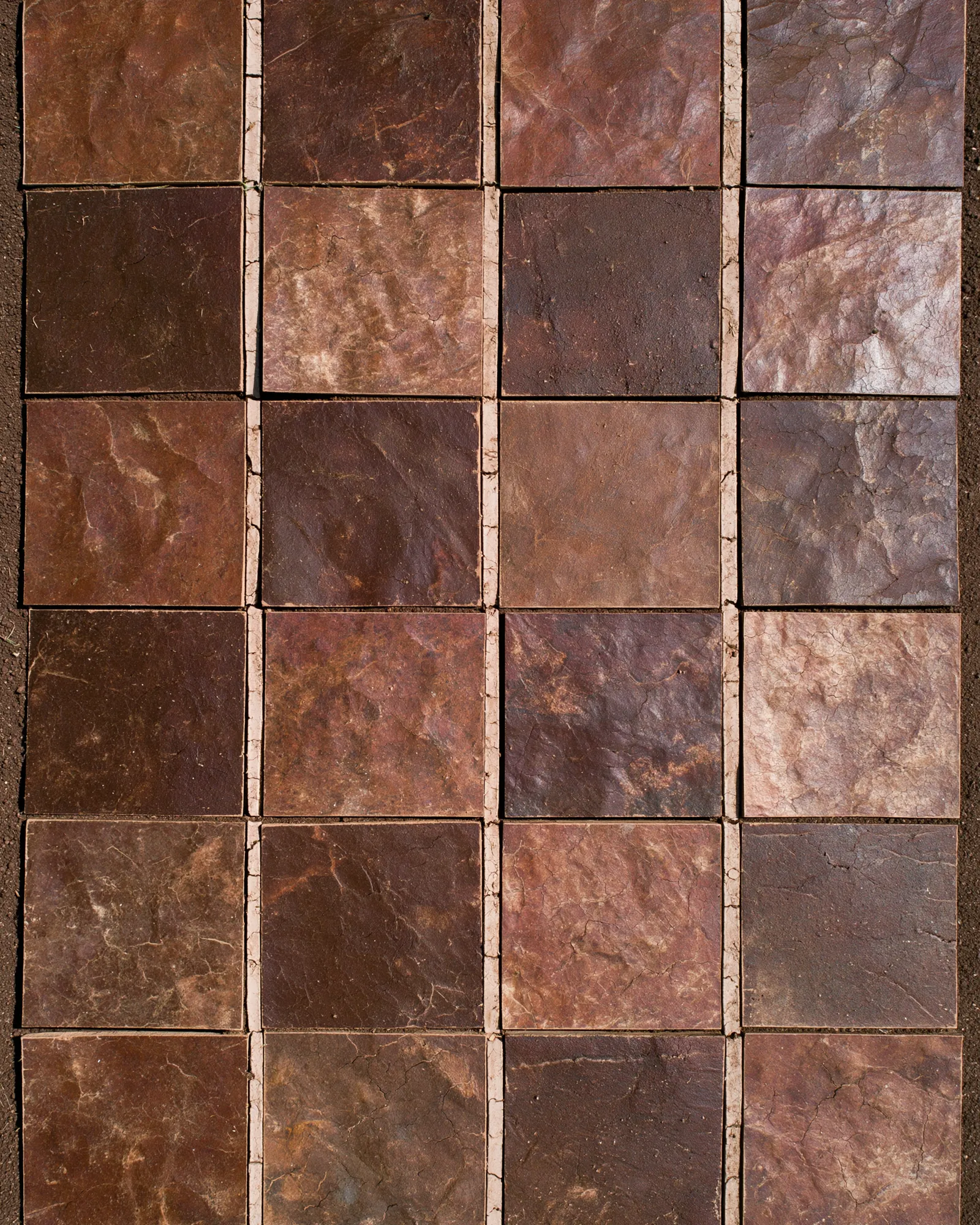 Squares of brown and chocolate stone laid in a grid, seen from above, the inspiration for the Tadla Chocolate & Brown rug
