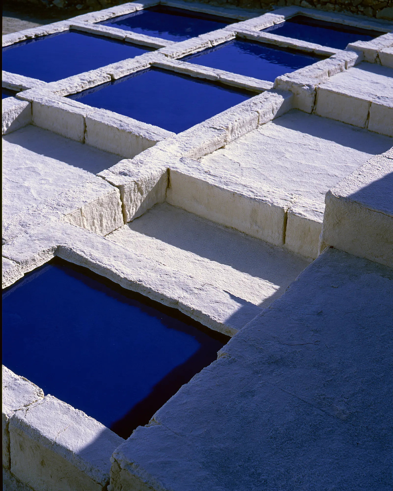 Square blue pools set in pale stone terraces, the inspiration for the Tarz Navy & Camel rug