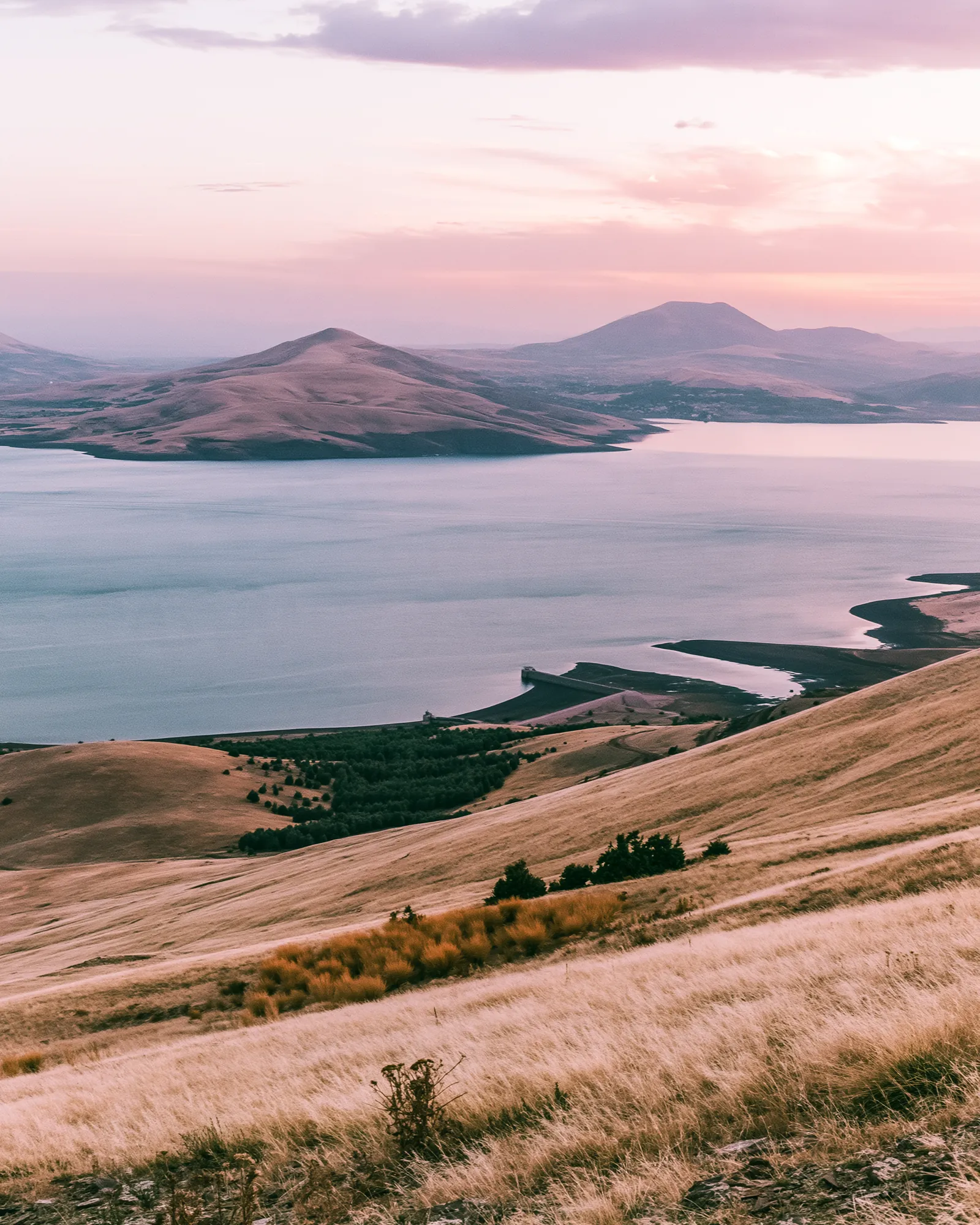 A lake under a blush pink sky, with hills along its shore, the inspiration for the Tislit Blush & Black rug