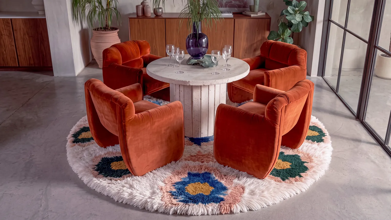 Lazward Cobalt & Mustard round hand-knotted Berber rug under a travertine dining table with rust velvet chairs