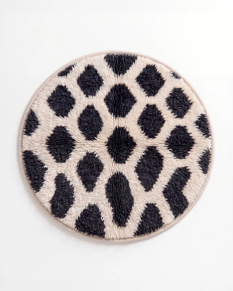 Black and ivory lozenge round hand-knotted wool rug photographed from overhead